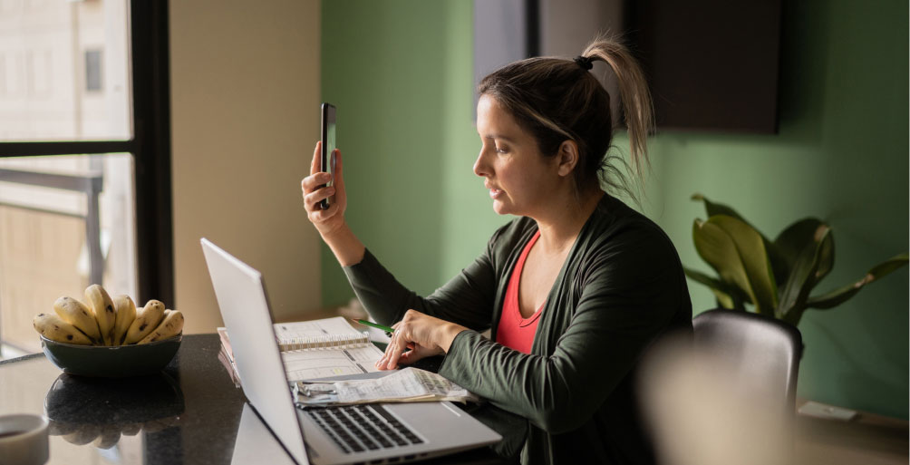 Woman sitting at table with phone and computer