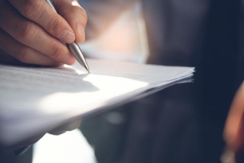 Person signing a contract on paper.