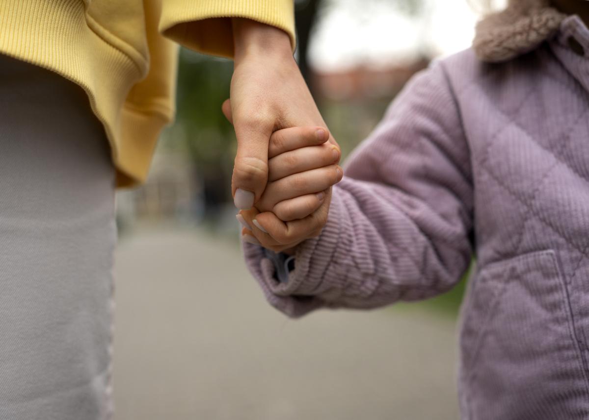 Parent holding child's hand.